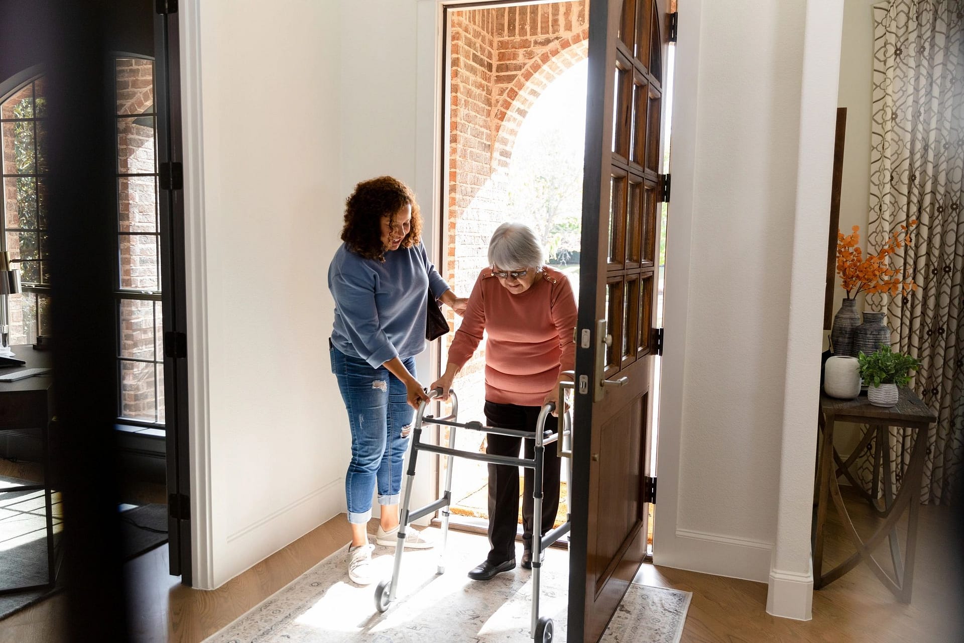 Woman helping a senior adult safely enter her home
